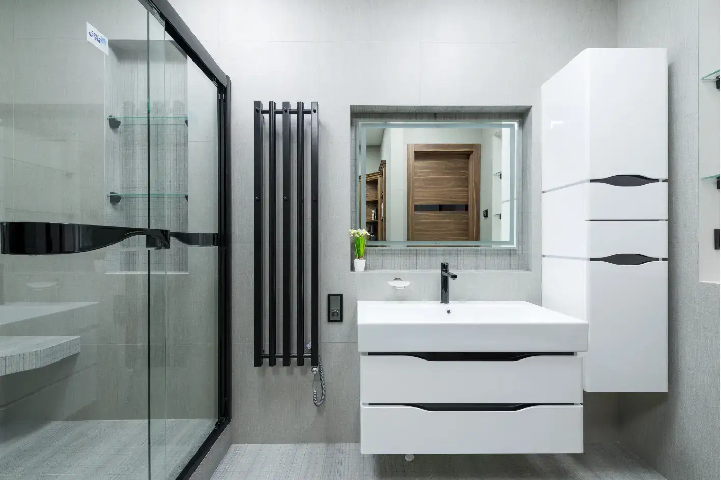 Siyah profilli duşakabin, siyah havlupan ve modern banyo dolapları.